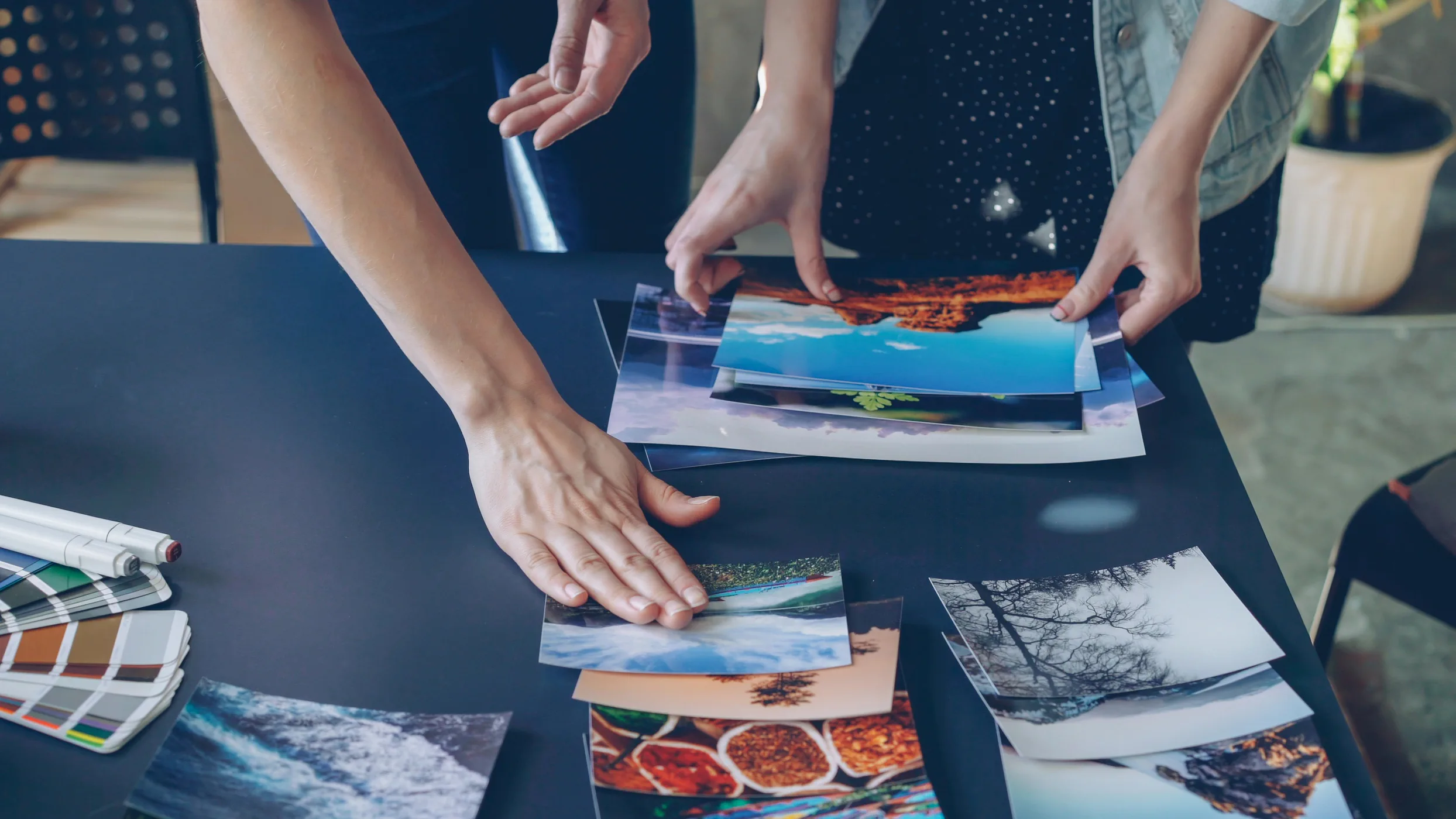 Hands laying out printed photographs on a table